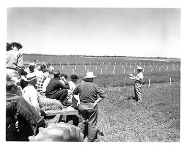 UMN professor speaks to farmers on a hayrack at a field day